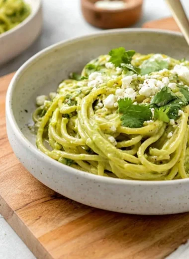 Plate of creamy Mexican green spaghetti garnished with cilantro and chili