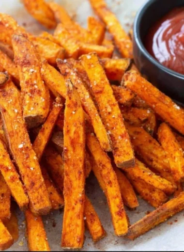 Crispy baked sweet potato fries on a plate, garnished with herbs