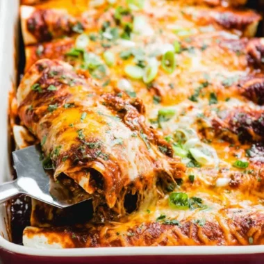Beef enchiladas topped with cheese and red sauce on a plate