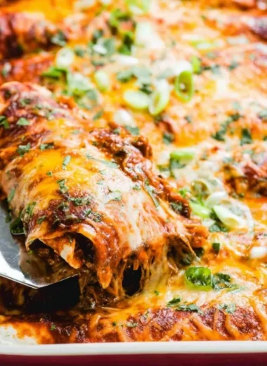 Beef enchiladas topped with cheese and red sauce on a plate
