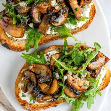 Creamy mushroom toast topped with herbs and spices, served on toasted bread.