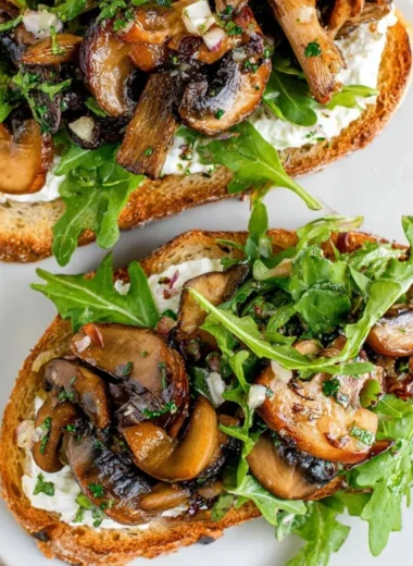 Creamy mushroom toast topped with herbs and spices, served on toasted bread.
