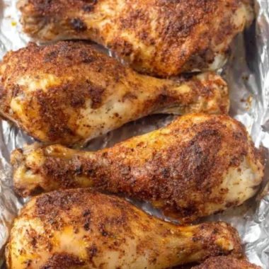 Crispy baked chicken legs on a serving plate garnished with herbs