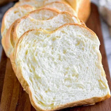 Freshly baked homemade white bread loaf on a wooden cutting board.