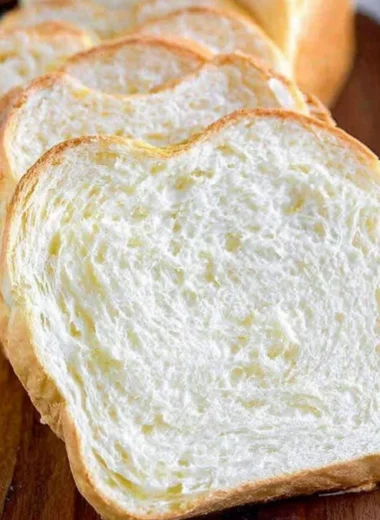 Freshly baked homemade white bread loaf on a wooden cutting board.