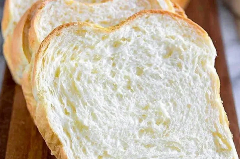 Freshly baked homemade white bread loaf on a wooden cutting board.