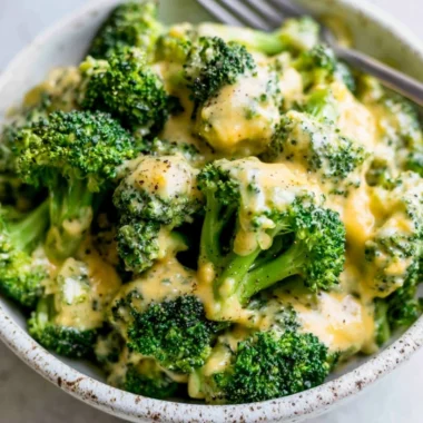 A delicious serving of cheesy broccoli topped with melted cheese.