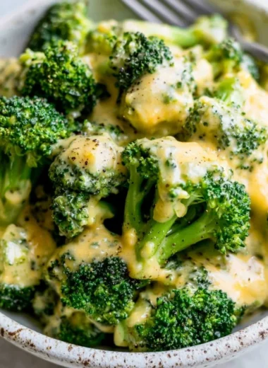 A delicious serving of cheesy broccoli topped with melted cheese.