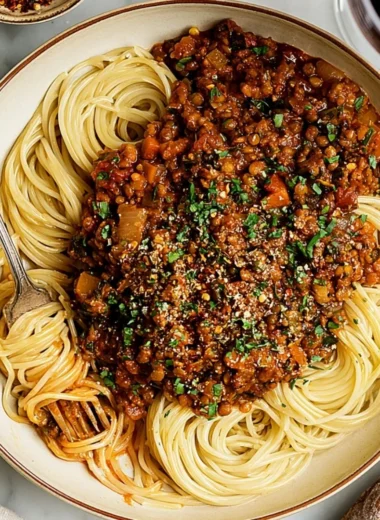 Bowl of Vegan Lentil Bolognese served with spaghetti and fresh herbs