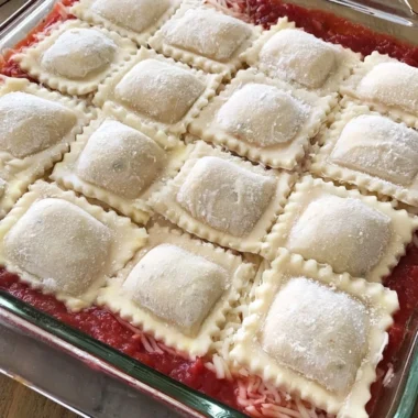 Baked ravioli casserole topped with cheese and herbs in a baking dish