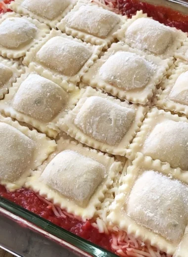 Baked ravioli casserole topped with cheese and herbs in a baking dish