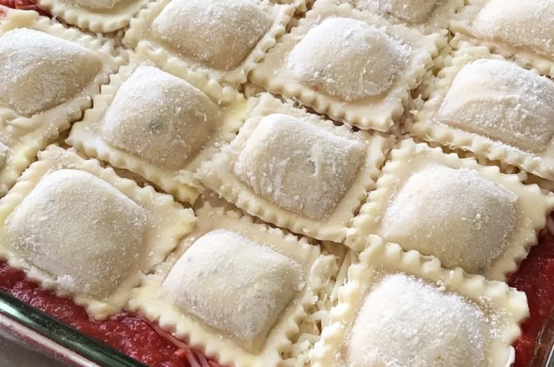 Baked ravioli casserole topped with cheese and herbs in a baking dish