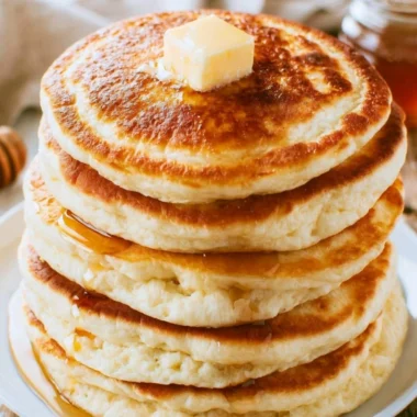 Stack of delicious fluffy pancakes topped with berries and syrup.