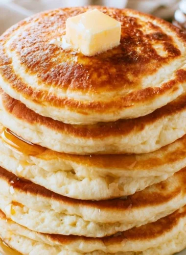 Stack of delicious fluffy pancakes topped with berries and syrup.