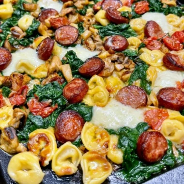 Plate of Blackstone Sausage with tortellini and spinach garnished
