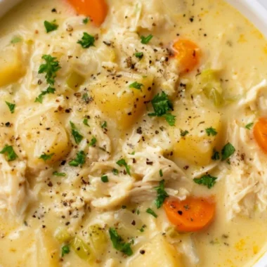 Bowl of Chicken Pot Pie Soup garnished with herbs and vegetables.