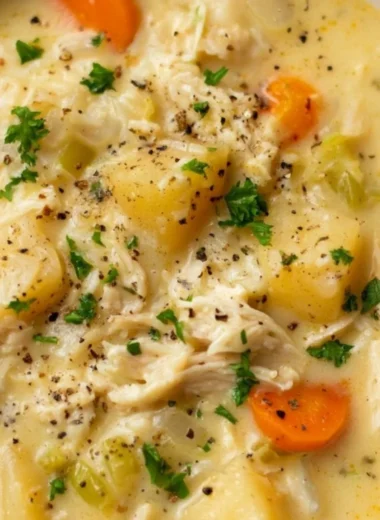 Bowl of Chicken Pot Pie Soup garnished with herbs and vegetables.