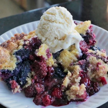 Fresh blackberry dump cake topped with whipped cream and berries
