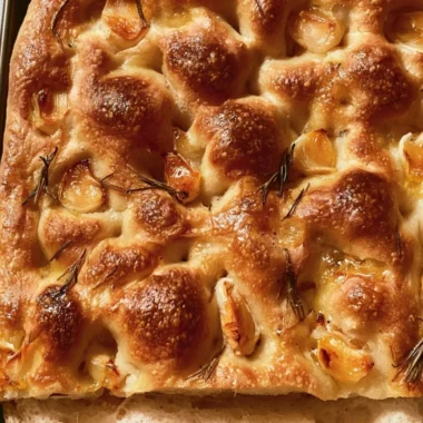 Slice of easy sourdough focaccia topped with herbs and olive oil