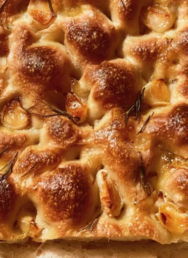 Slice of easy sourdough focaccia topped with herbs and olive oil
