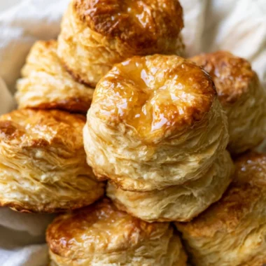 Fluffy homemade buttermilk biscuits on a plate with butter and herbs.