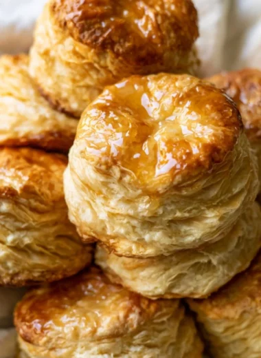 Fluffy homemade buttermilk biscuits on a plate with butter and herbs.