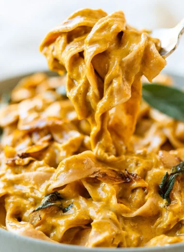 Pumpkin pasta sauce served over noodles, garnished with herbs.
