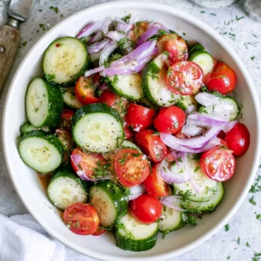 Fresh tomato cucumber salad with red onion and herbs in a bowl