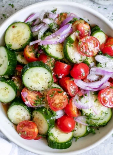 Fresh tomato cucumber salad with red onion and herbs in a bowl