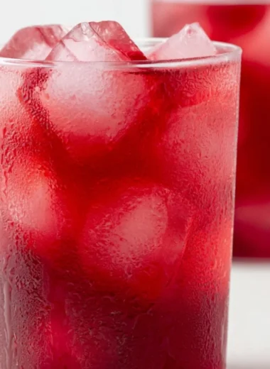 A refreshing glass of strawberry hibiscus iced tea with fresh berries and hibiscus flowers.