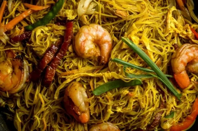 A plate of colorful Singapore Noodles with shrimp and vegetables